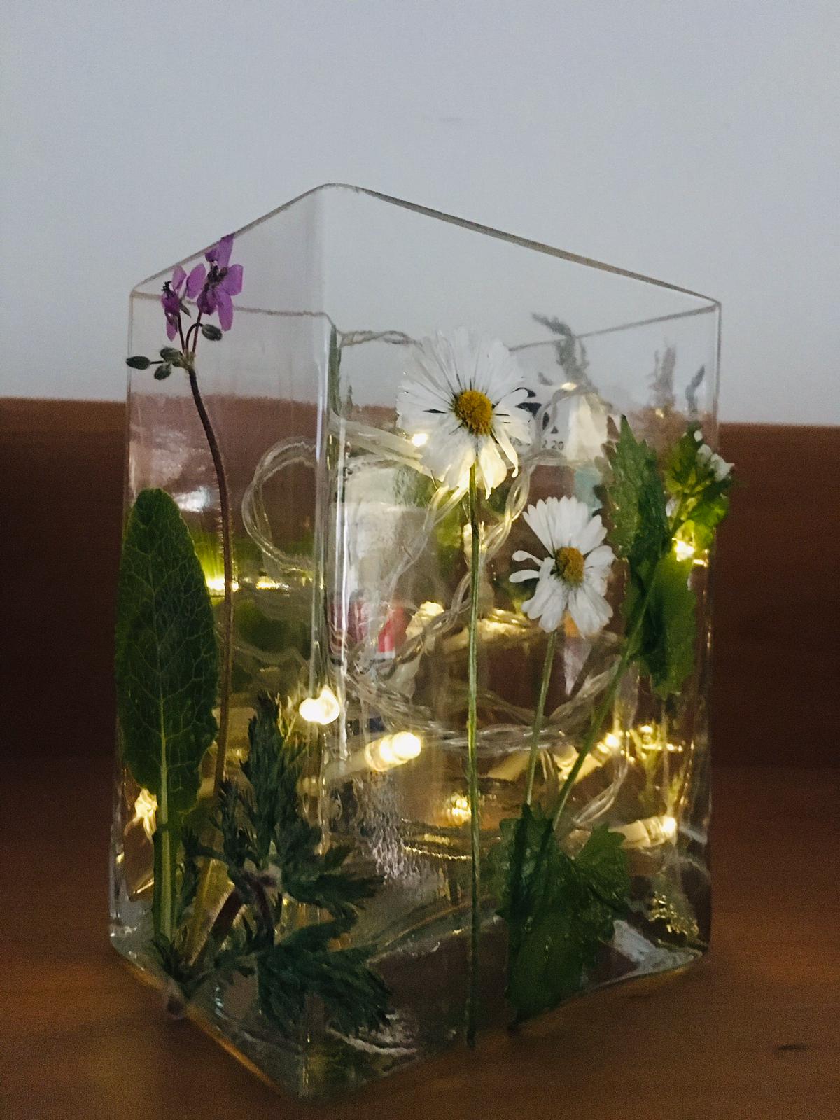 Die Gläser mit verschiedenen Blättern, Blüten und Grashalmen bekleben und anschließend eine Kerze und Lichterkette ins Glas tun. Durch die Wärme verfärben sich die Pflanzen nach einer Weile dunkel. Wiesenwindlicht 02