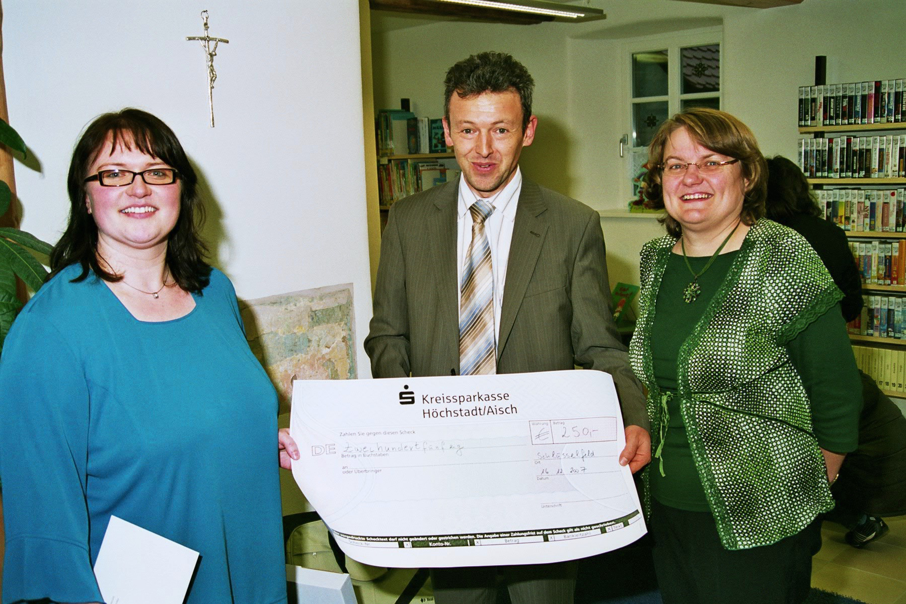 Geschäftsstellenleiter Harald Goller überreicht den Scheck an die Büchereileiterinnen Sabine Litz (links) und Christine Wittenbauer (r) Scheckübergabe Bücherei